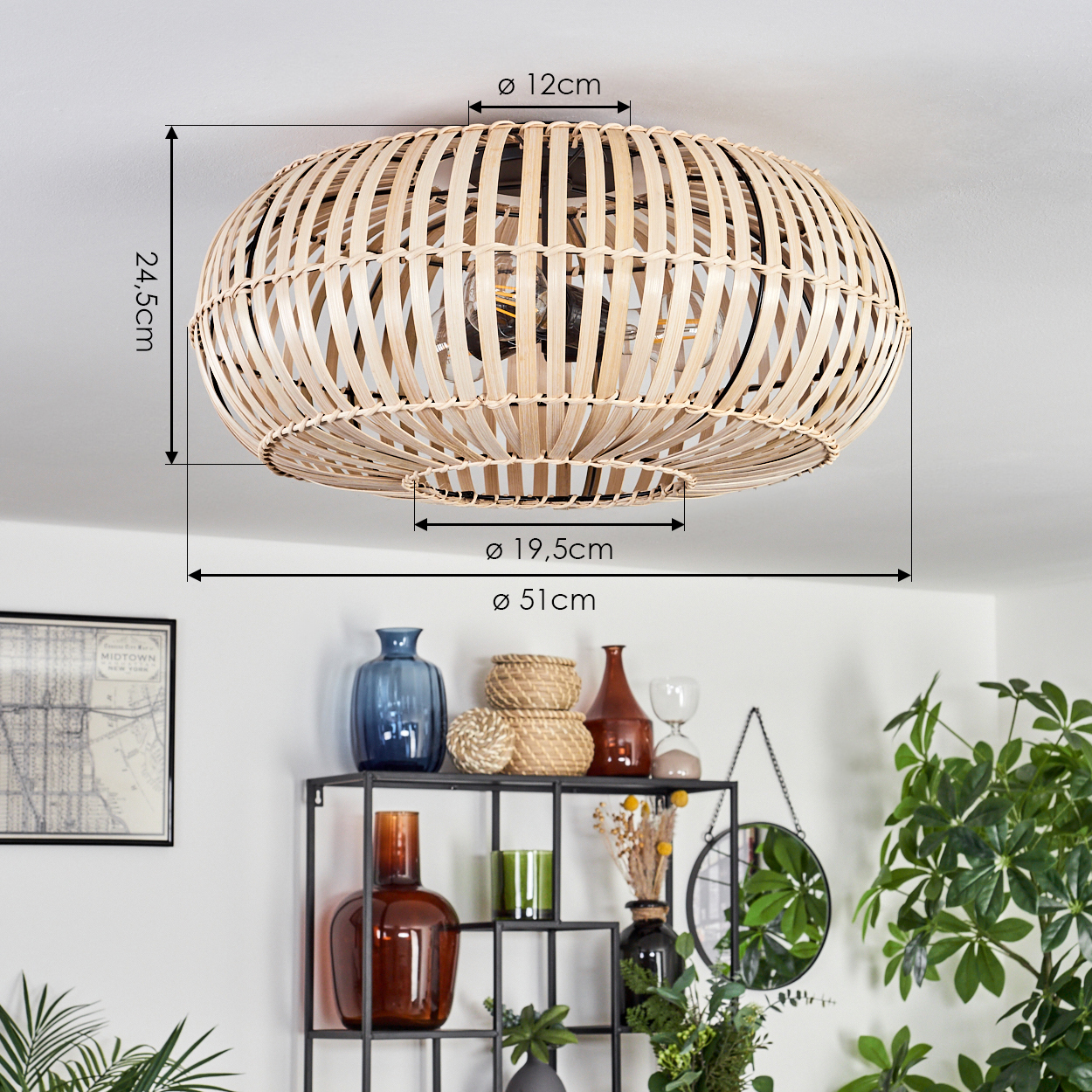 Eine Deckenlampe aus geflochtenem Rattan mit Beschriftungen. Darunter ein schwarzes Regal mit Vasen, Deko und Spiegel, mit Grün.