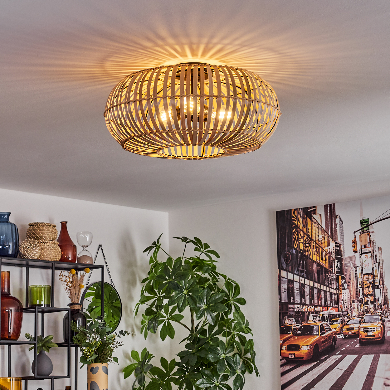 Ein Bambus-Lampenschirm hängt an der Decke. Darunter ein Regal mit Vasen und einer Pflanze. Ein New York City-Bild an der Wand.