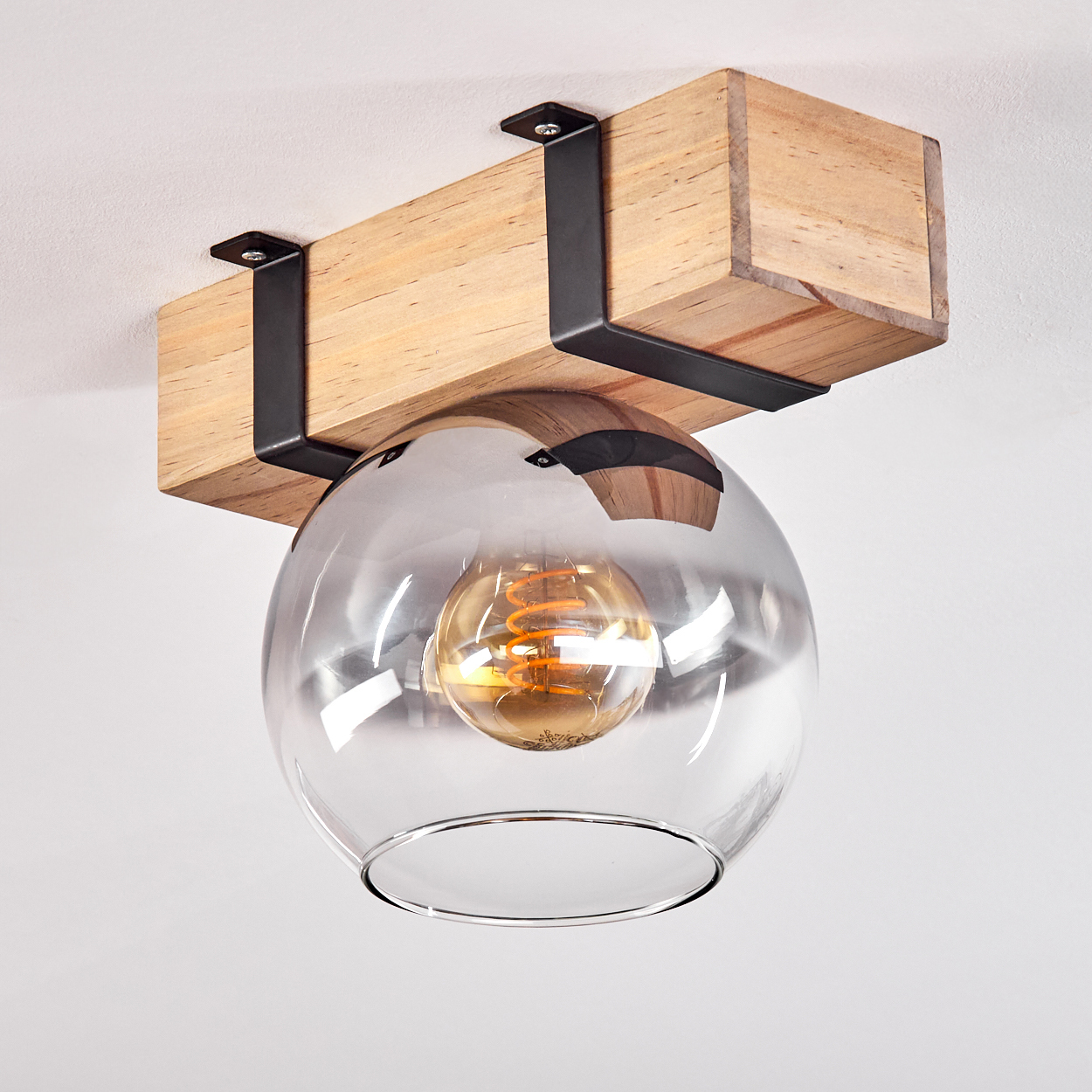 Eine Deckenleuchte mit Holzbalken, schwarzen Metallstützen und einem klaren Glaskugel mit Glühbirne.