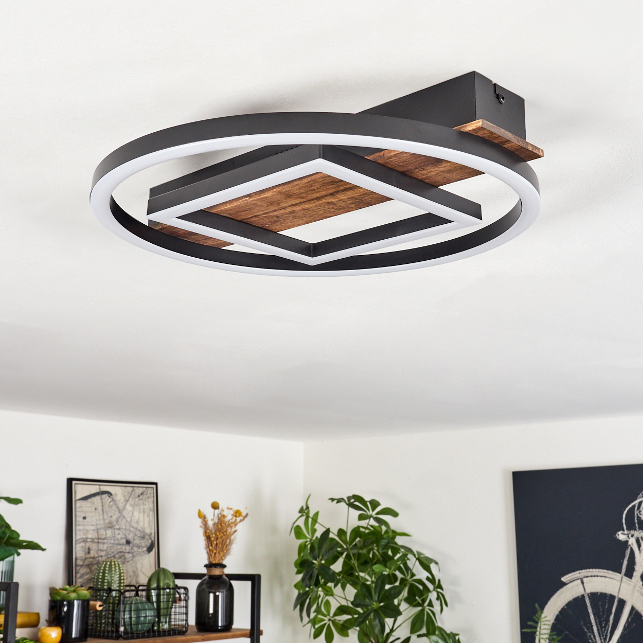 Moderne Deckenleuchte mit schwarzem Rahmen, weißem Licht und Holzakzenten. Der Raum hat Dekor und Pflanzen.
