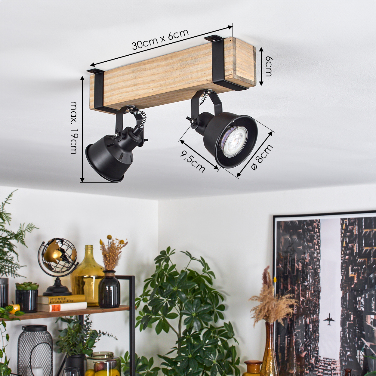 Schwarze Strahler an einem Holzbalken montiert. Maße sind angegeben. Regal mit Globus, Pflanzen und Dekorationsgegenständen im Hintergrund.