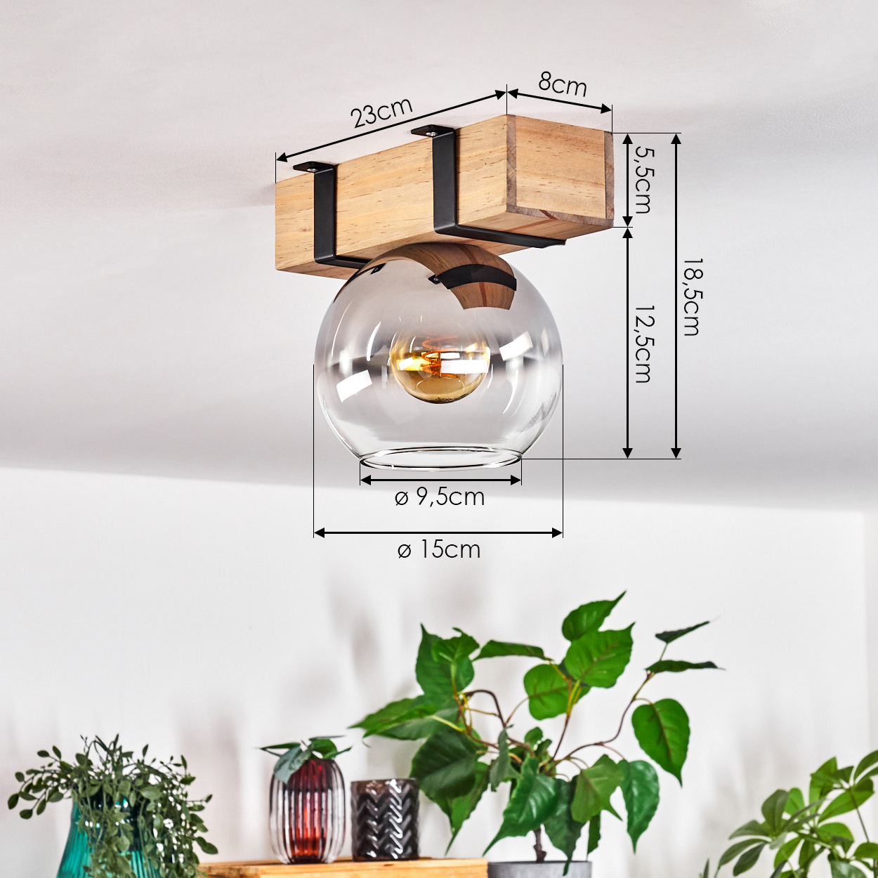 Deckenlampe mit Holzbalken und Glaskugel. Abmessungen sind angegeben. Grüne Pflanzen im Vordergrund.