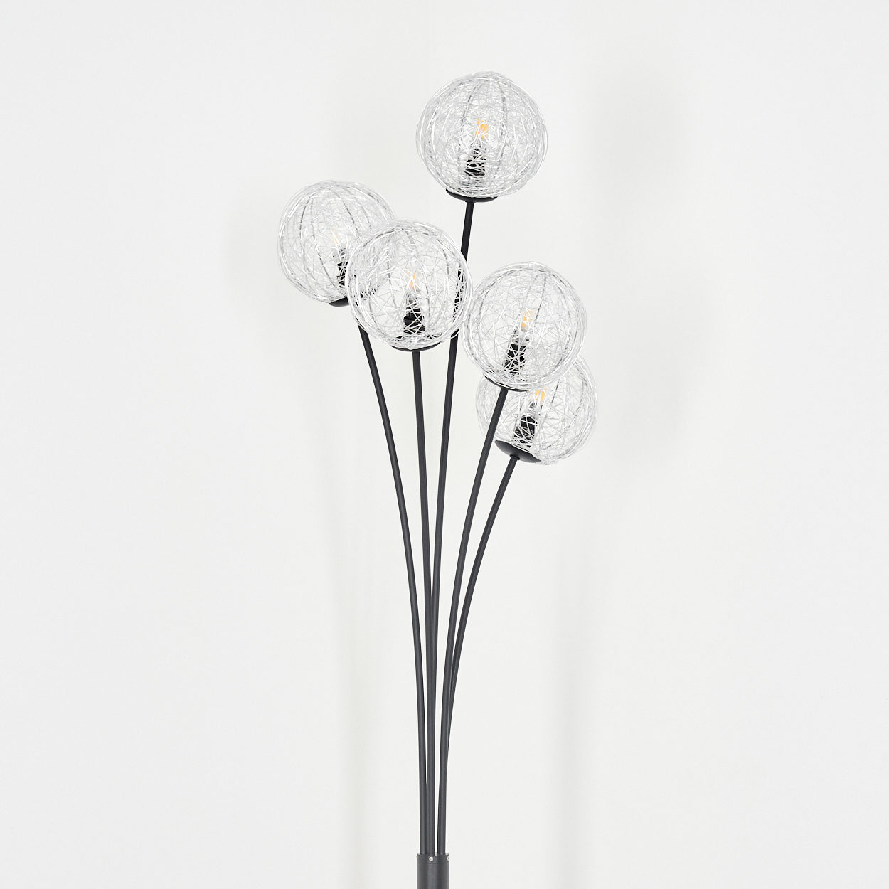 Eine Stehlampe mit fünf kugelförmigen Drahtgestell-Schirmen. Die Lampe hat einen schwarzen Stiel und Sockel vor einer weißen Wand.