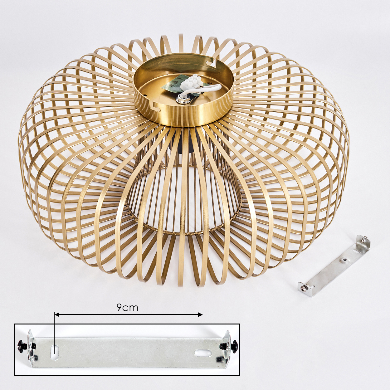 Goldener Metalllampenschirm auf weißem Hintergrund. Daneben eine Metallhalterung. Auf einer Halterung ist ein Maß von 9 cm markiert.