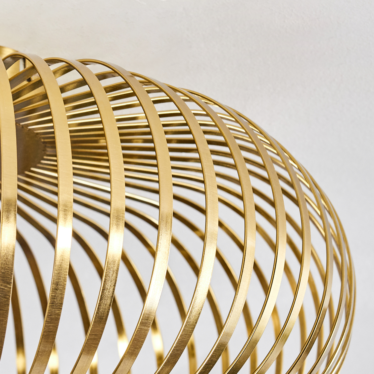 Nahaufnahme einer goldfarbenen, kugelförmigen Leuchte. Das Design weist gebogene, vertikale Metallstreifen vor weißem Hintergrund auf.