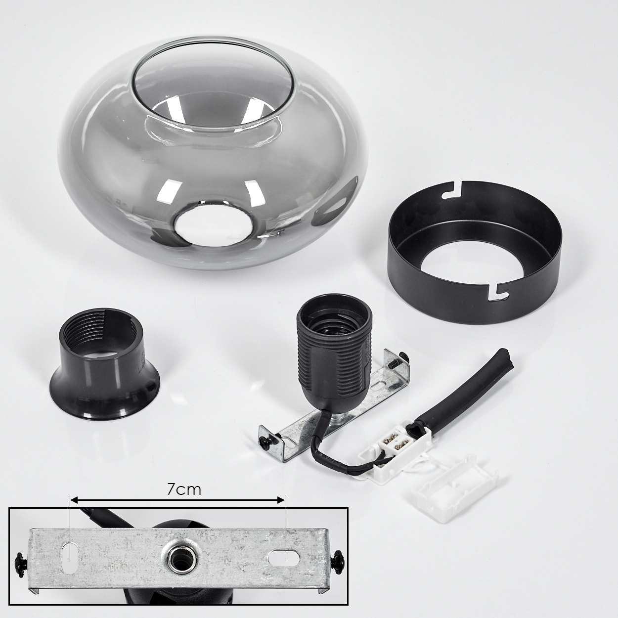 Zerlegte Lampenteile: Glasschirm, schwarzer Ring, Lampenfassung, Sockel und elektrische Komponenten auf weißer Oberfläche.