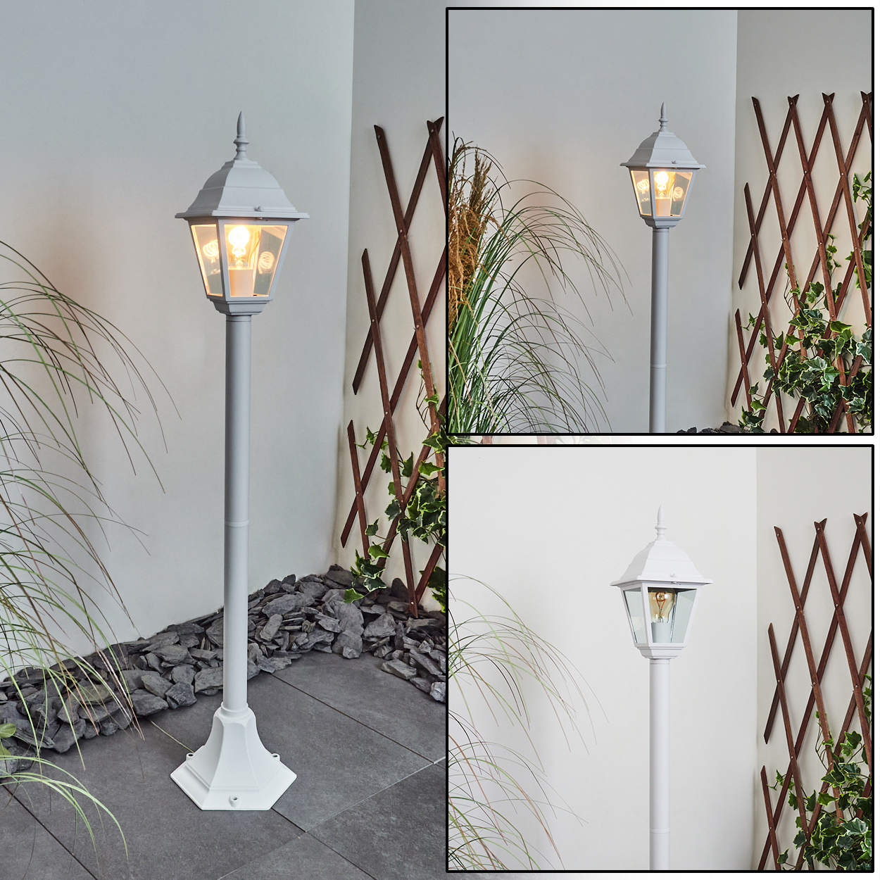 Eine weiße Außenlampe steht auf einer gepflasterten Oberfläche. Grüne Pflanzen und ein Holzgitter befinden sich im Hintergrund.
