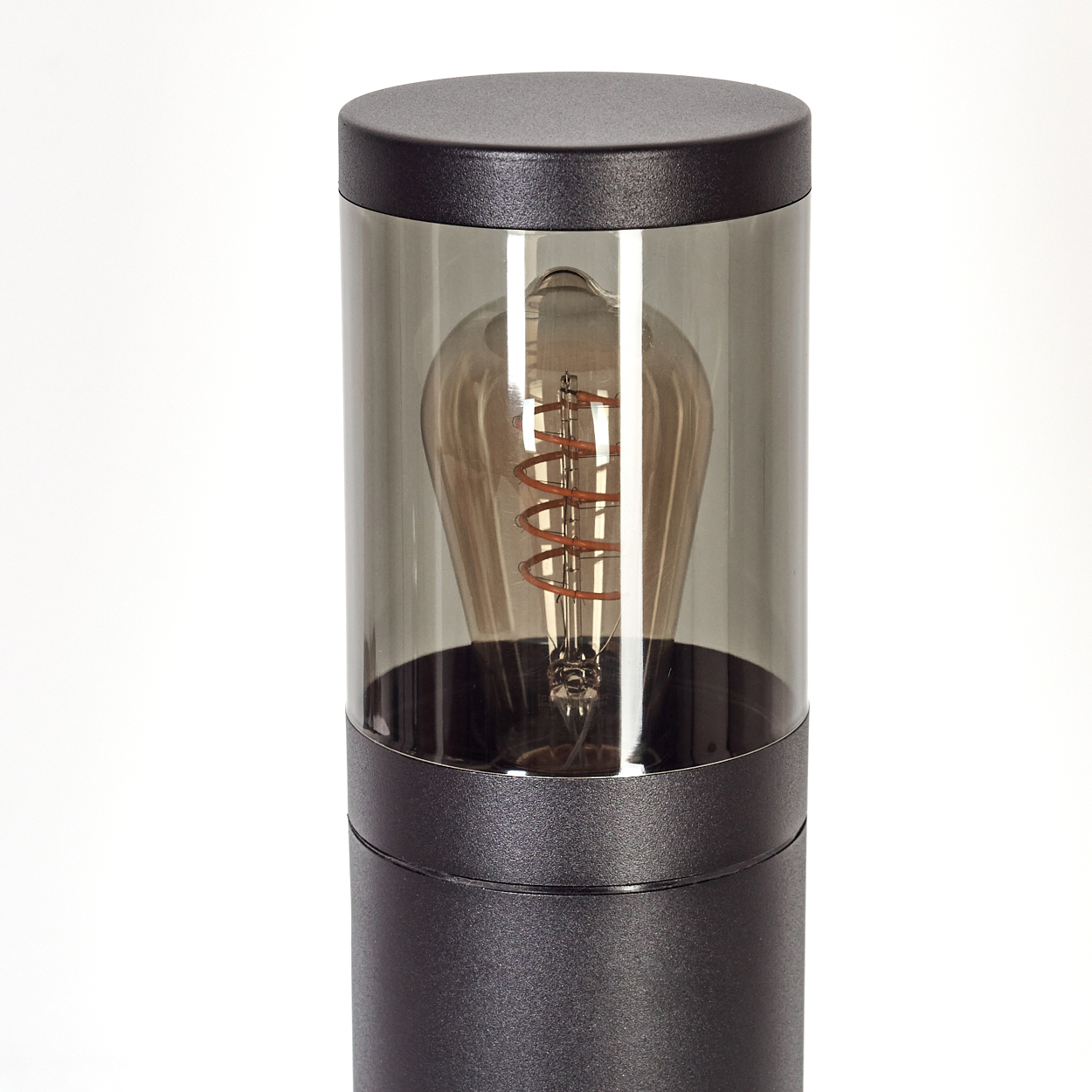 Eine moderne Lampe mit dunkelgrauem Glasschirm. Im Inneren leuchtet eine Glühbirne im Vintage-Stil mit sichtbarem Wendel.