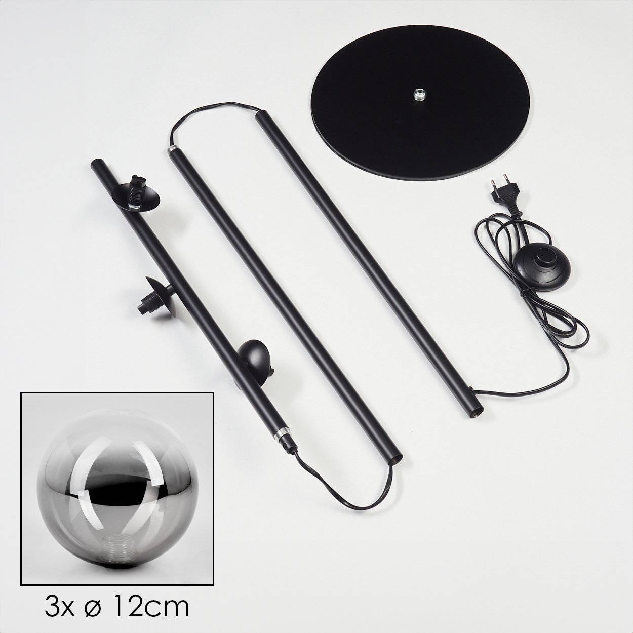 Schwarze Stehlampenteile auf Weiß. Enthält Basis, Stangen, Netzkabel und drei Glaskugelleuchten in einer Box.
