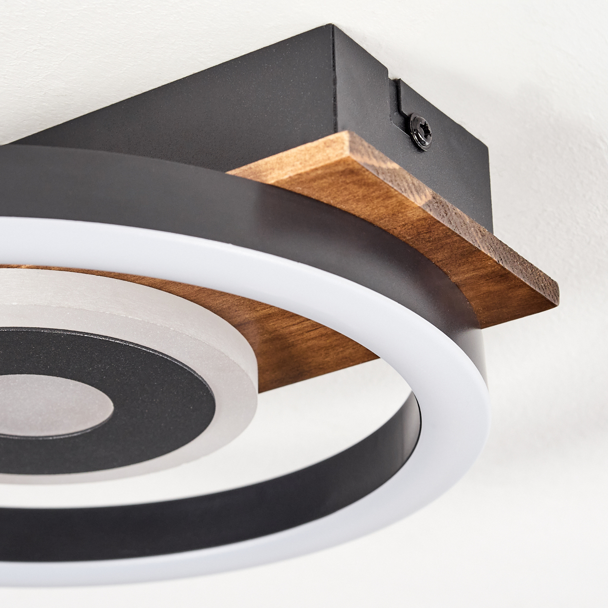 Eine moderne Deckenlampe mit einem schwarz-weißen kreisförmigen Design, Holzakzenten und einer weißen Decke im Hintergrund.