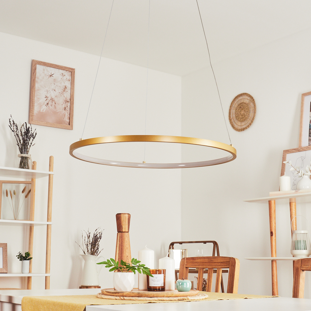 Eine goldene kreisförmige Leuchte hängt über einem Esstisch. Der Raum ist mit Regalen, Kerzen und Kunstwerken dekoriert.