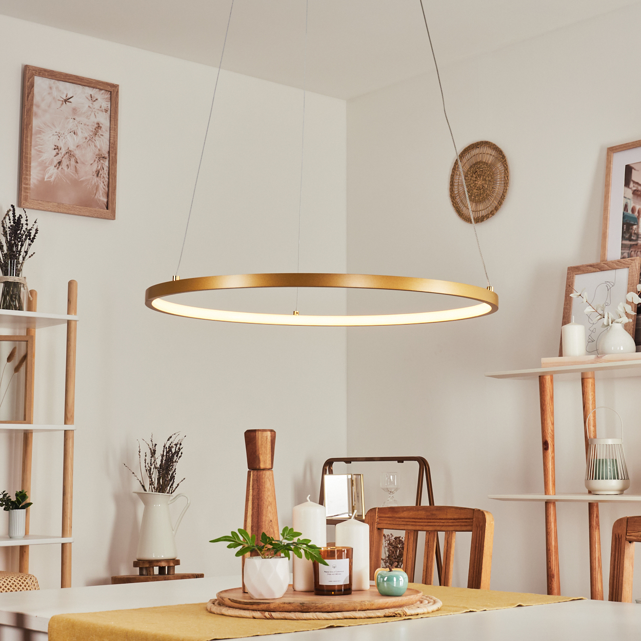 Ein modernes Esszimmer mit goldenem kreisförmigen Kronleuchter, weißen Wänden und einem Tisch mit Dekoration. Ein Holzstuhl ist sichtbar.