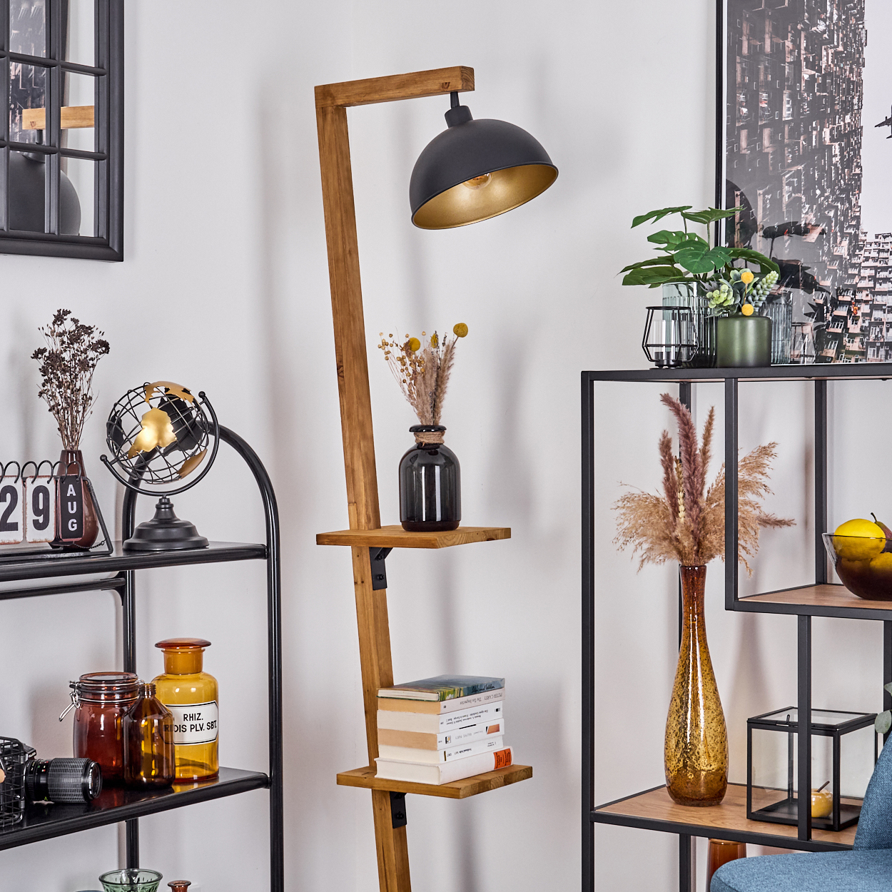 Eine Stehlampe aus Holz mit schwarzem Schirm. Regale mit Büchern, Vasen und Dekorationen. Ein schwarzes Metallregal zeigt weitere Gegenstände.