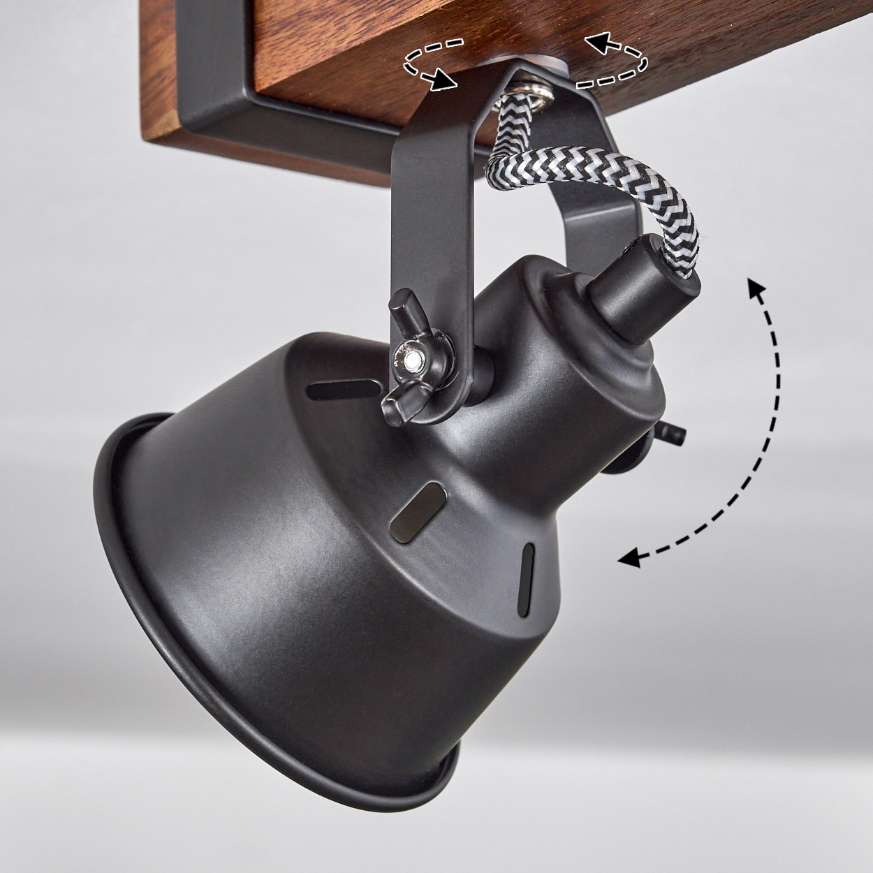 Eine schwarze Strahlerhalterung ist an einem Holzbalken befestigt. Sie hat verstellbare Winkel. Das Kabel ist schwarz-weiß.