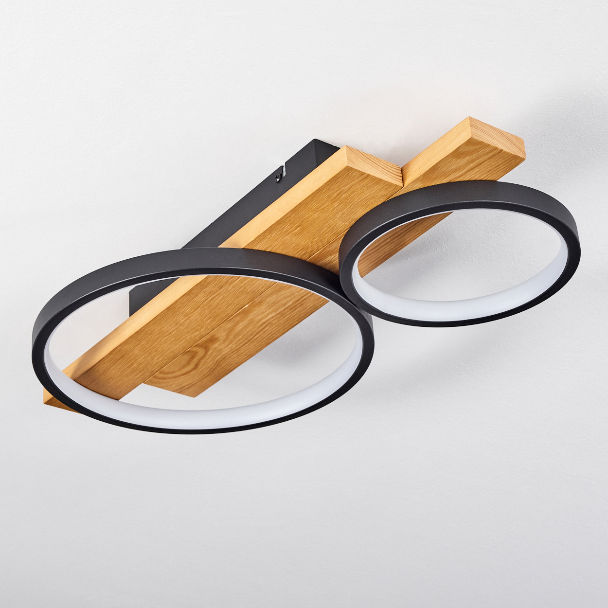 Moderne Deckenleuchte. Verfügt über zwei schwarze kreisförmige Lichter mit weißen Innenringen, die an einem Holz- und schwarzen Rahmen befestigt sind.
