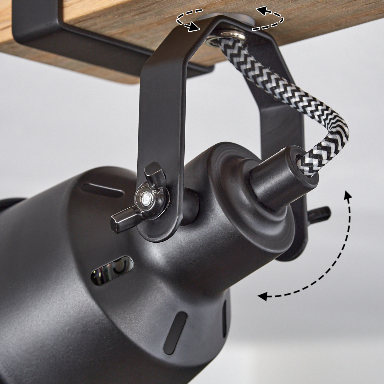 Ein schwarzer Strahler an Holz befestigt, mit einem schwarz-weißen Kabel. Es ist an einer Holzoberfläche montiert. Der Winkel ist einstellbar.