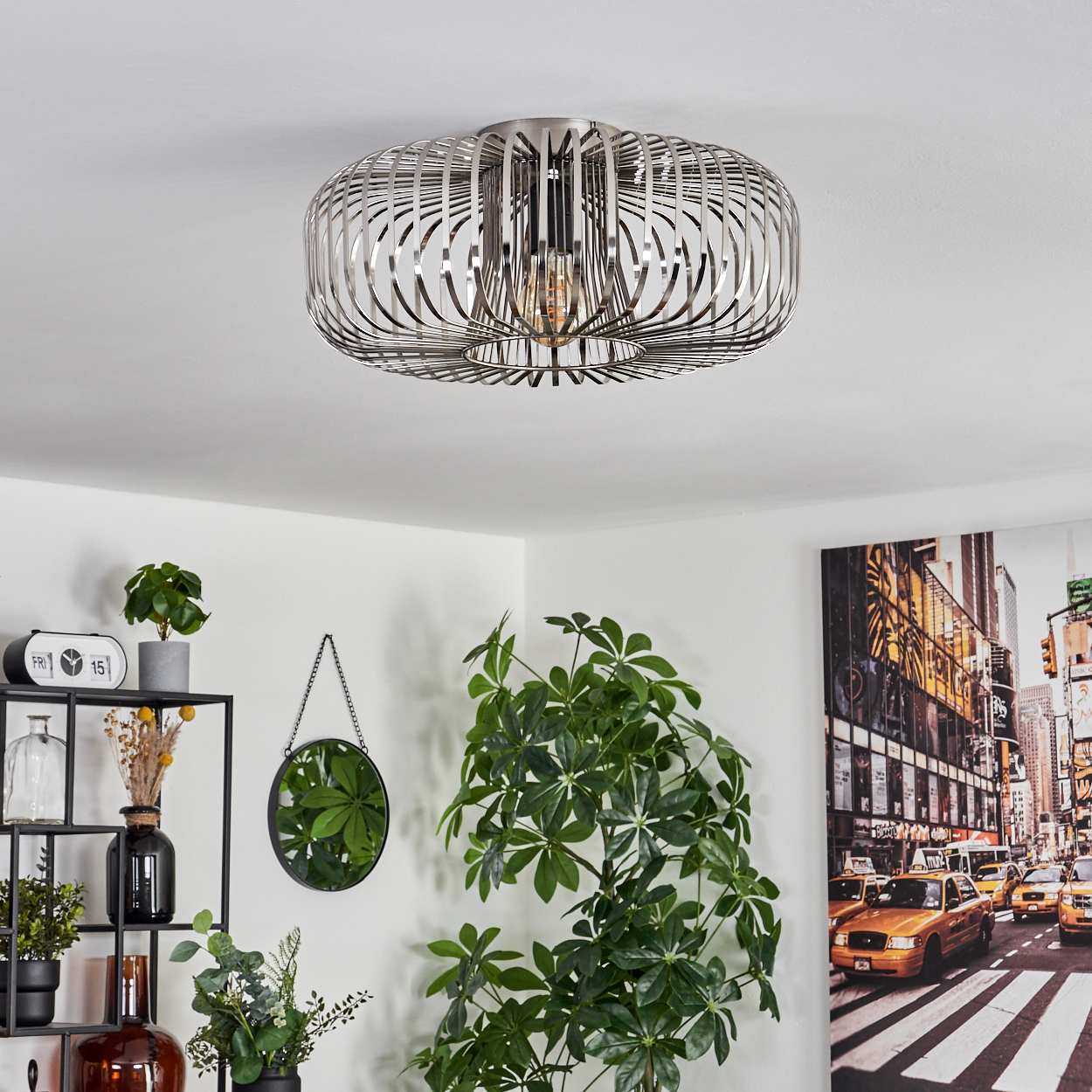 Moderne Deckenleuchte mit Metallrahmen. Darunter ein Raum mit Pflanzen, einem Spiegel und einem Gemälde einer New Yorker Straßenszene.
