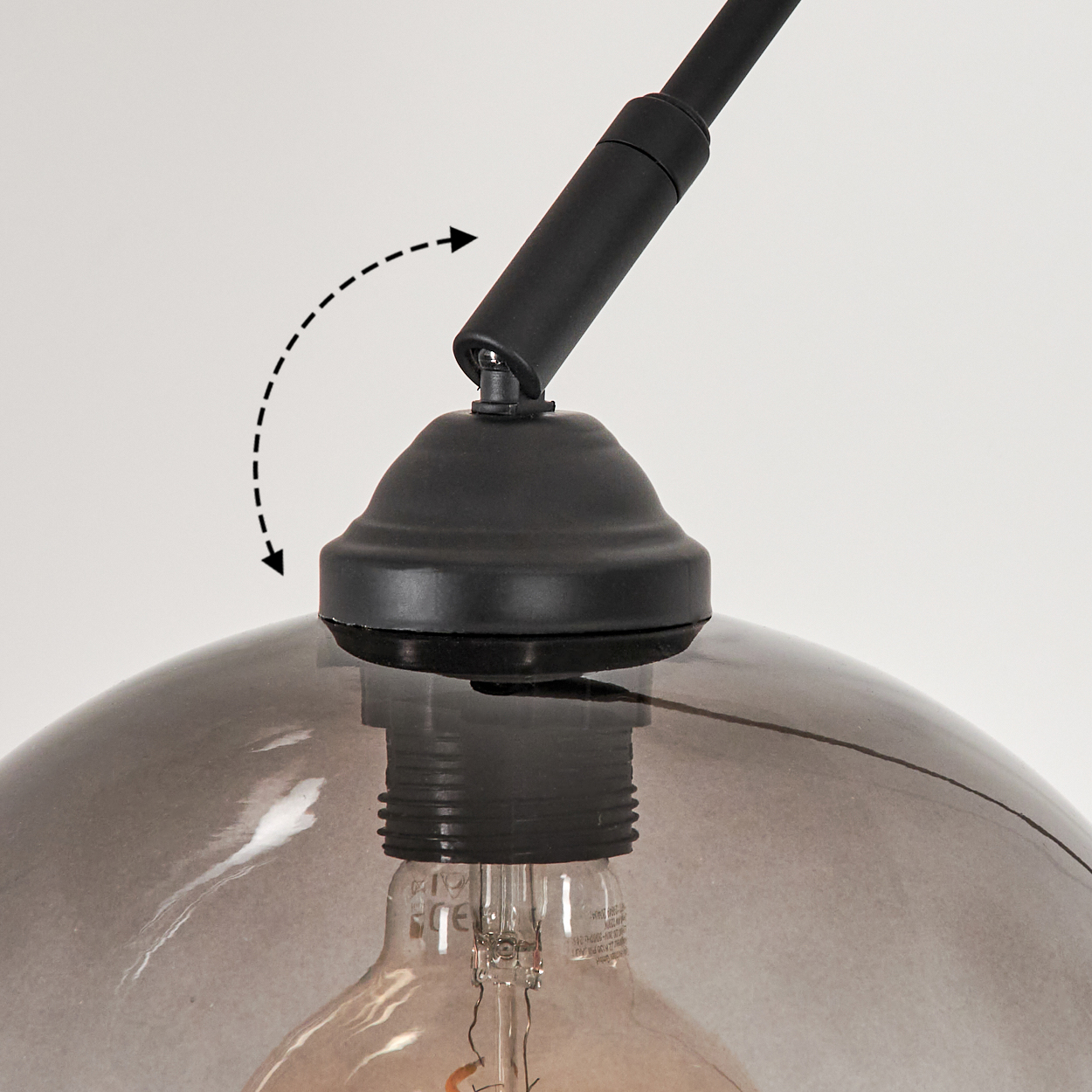Nahaufnahme einer schwarzen Lampenfassung. Ein transparenter, kuppelförmiger Lampenschirm bedeckt eine Glühbirne. Die Fassung hat einen schwarzen Arm und Sockel.