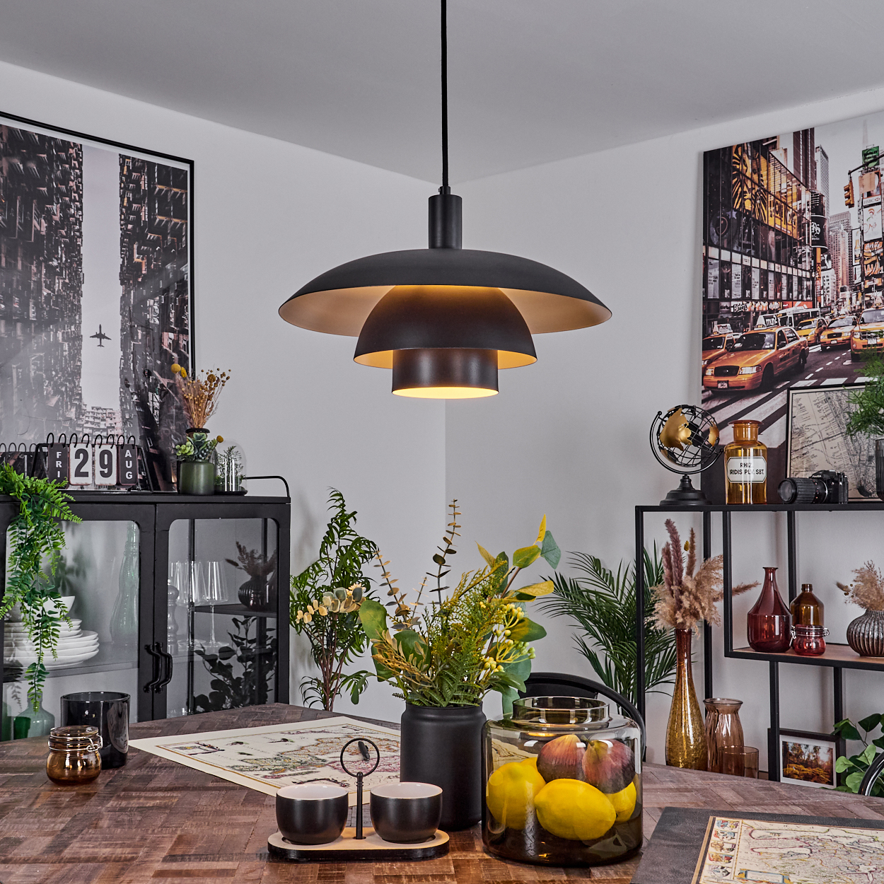 Ein Esszimmer mit schwarzer Lampe, Tisch und Dekorationen. Stadtlandschaftskunst an den Wänden. Früchte in einem Glas stehen auf dem Tisch.