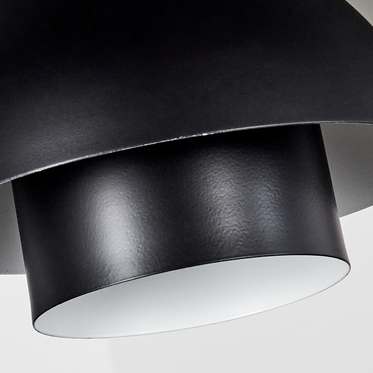 Nahaufnahme einer schwarzen, modernen Lampe. Die Lampe hat eine zylindrische Form mit weißem Innenraum und strukturierter Oberfläche.