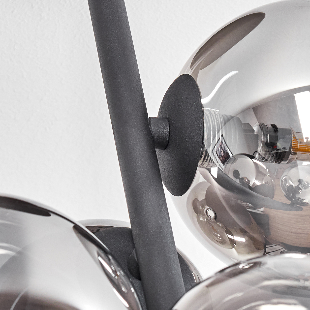 Nahaufnahme einer modernen Lampe. Graue Metallstangen und kreisförmige Platten tragen reflektierende Glaskugeln. Weißer Hintergrund.