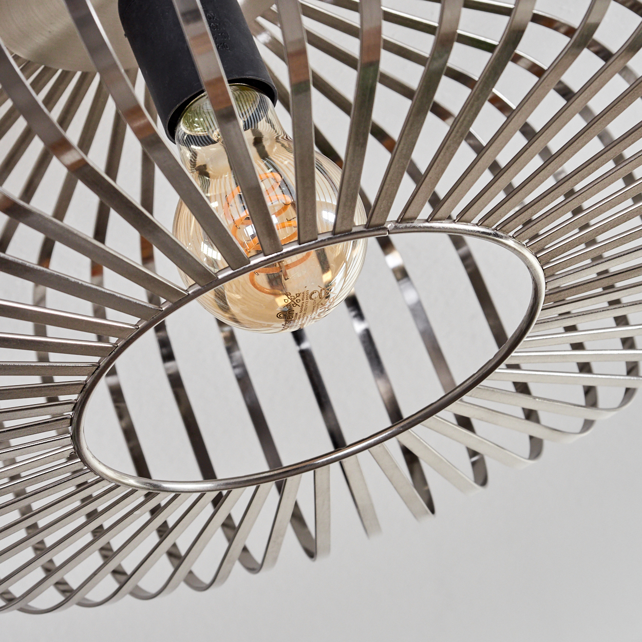Nahaufnahme einer modernen Lampe. Eine Glühbirne befindet sich in einem Metallrahmen. Der Hintergrund ist weiß.