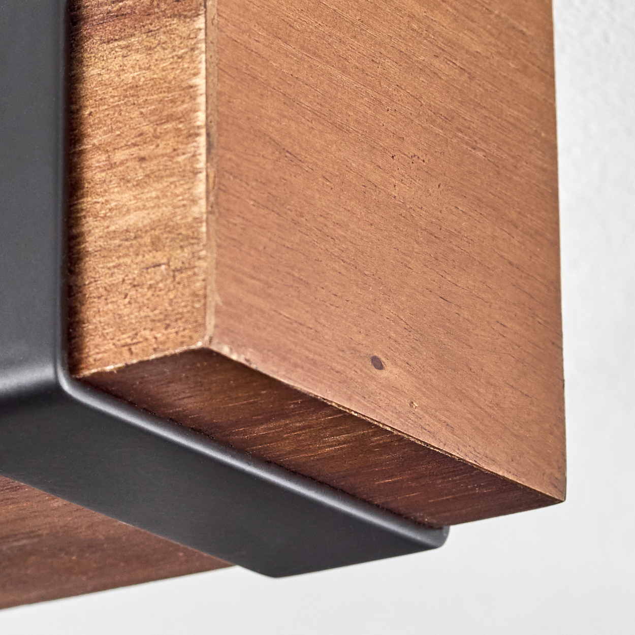 Nahaufnahme eines Holzbalkens mit einer schwarzen Metallhalterung. Das Holz ist braun mit sichtbarer Maserung. Der Hintergrund ist weiß.