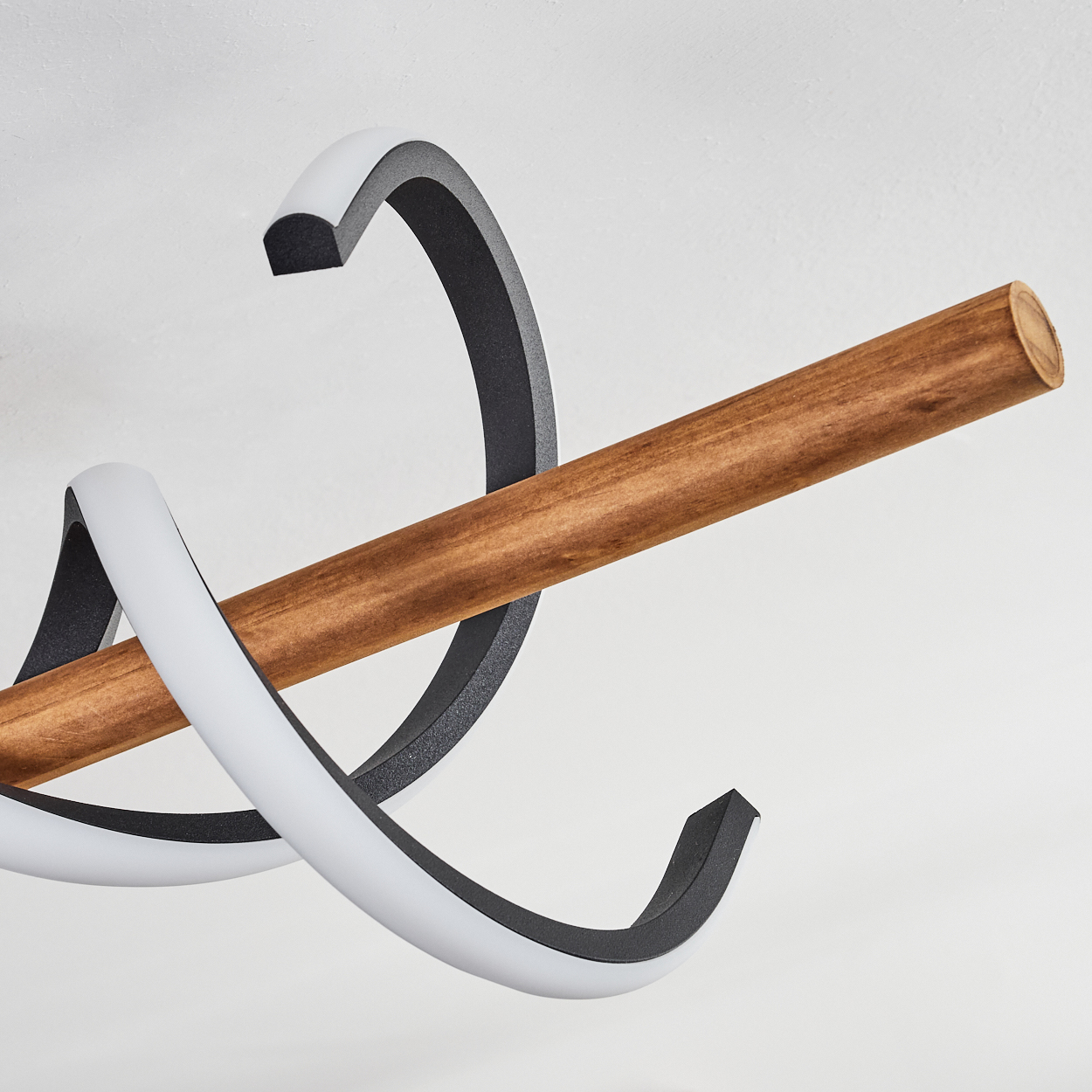 Eine moderne Leuchte mit einem Holzbalken und zwei schwarz-weißen, gebogenen Elementen auf weißem Hintergrund.