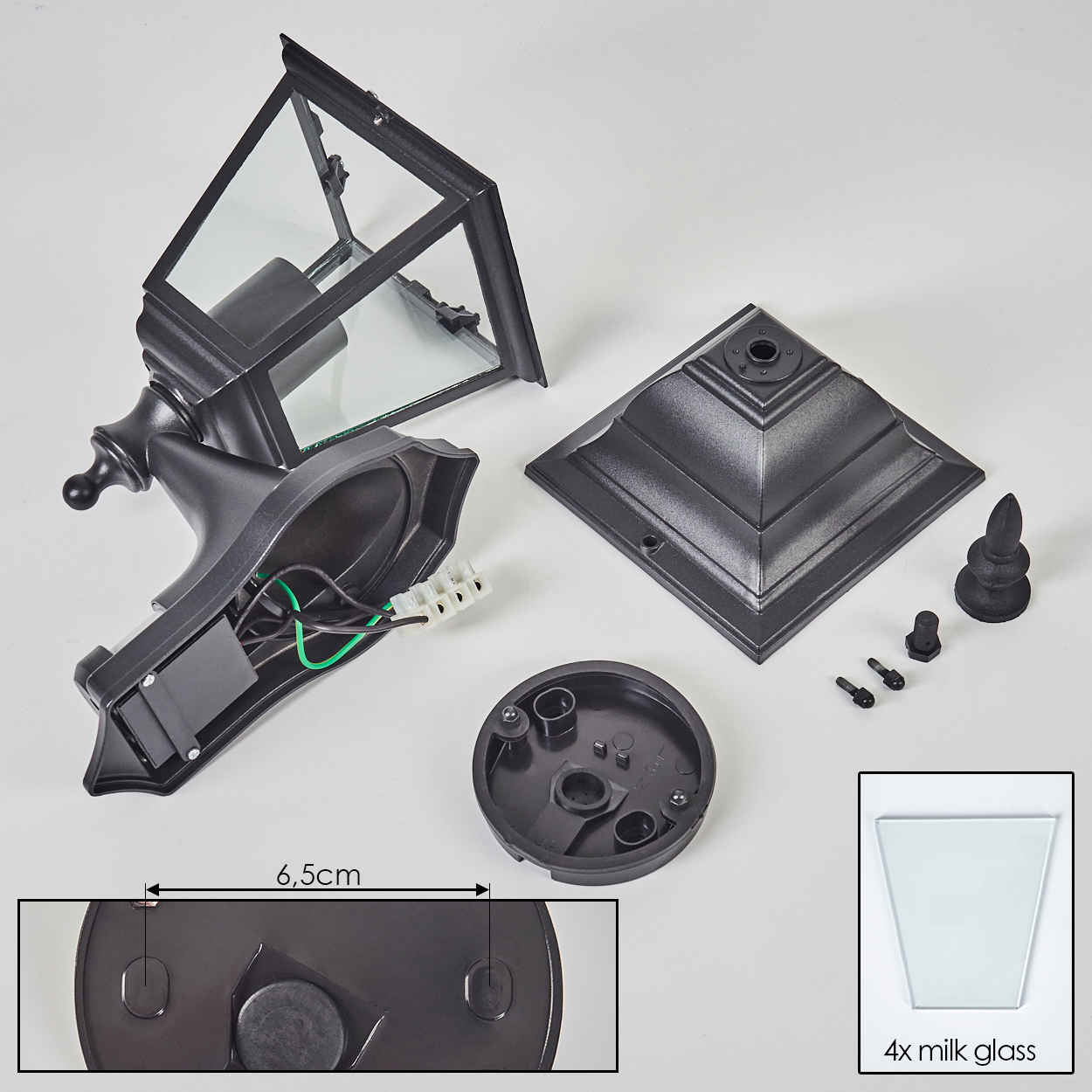 Zerlegte schwarze Außenlampenteile auf weißem Untergrund. Enthält Glasscheiben, Sockel, Drähte und Schrauben. 6,5 cm Maß.