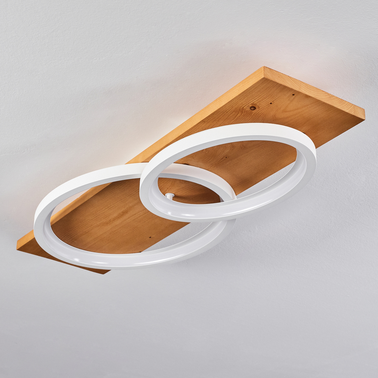 Eine moderne Deckenleuchte. Sie hat zwei weiße, kreisförmige Lichter, die sich mit einem Holzbrett kreuzen. Der Hintergrund ist eine weiße Decke.