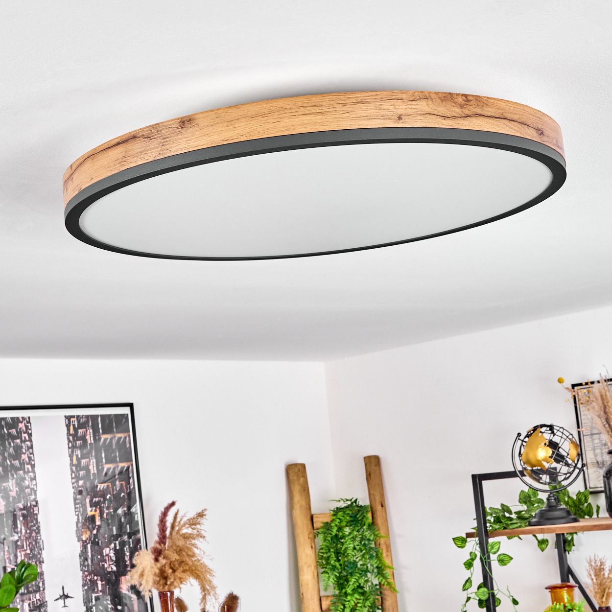Ovale Deckenleuchte mit Holzrahmen. Darunter ein Wohnzimmer mit Dekoration, einer Leiter und Kunstwerken an der Wand.