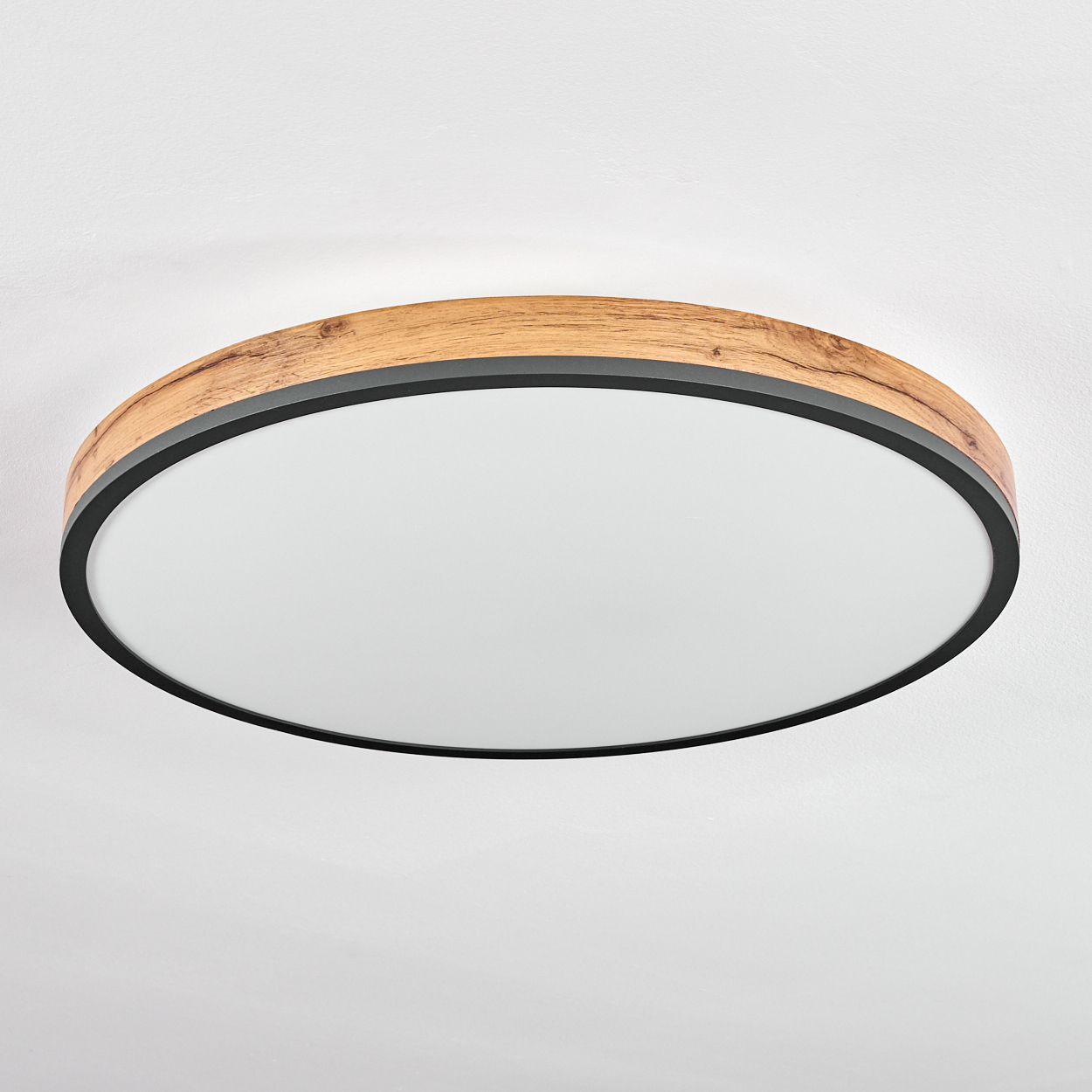 Eine runde Deckenlampe. Sie hat einen Holzrahmen mit schwarzem Rand und eine weiße, diffuse Lichtfläche in der Mitte.