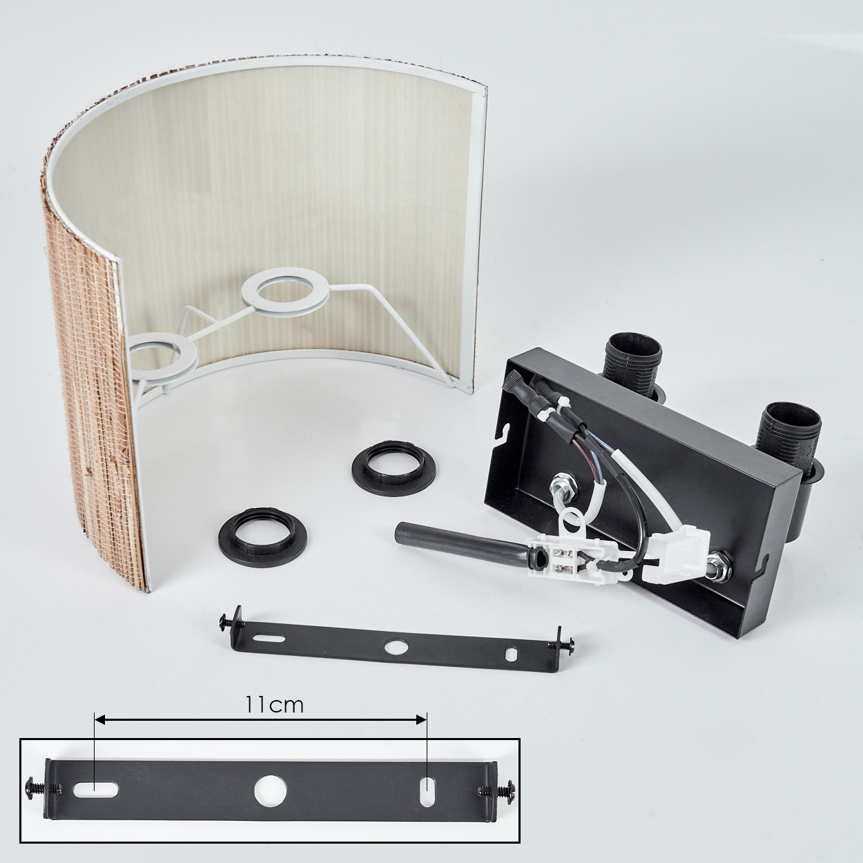 Eine zerlegte Lampe mit Lampenschirm, Montagebügel, elektrischen Komponenten und einem schwarzen Sockel. Die Halterung misst 11 cm.