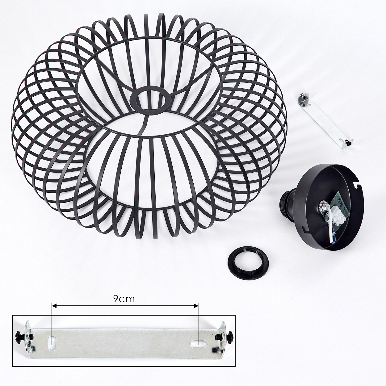 Ein schwarzer Drahtlampenschirm, Komponenten und eine Halterung liegen auf einer weißen Oberfläche. Maße sind 9 cm. Die Lampe ist zerlegt.