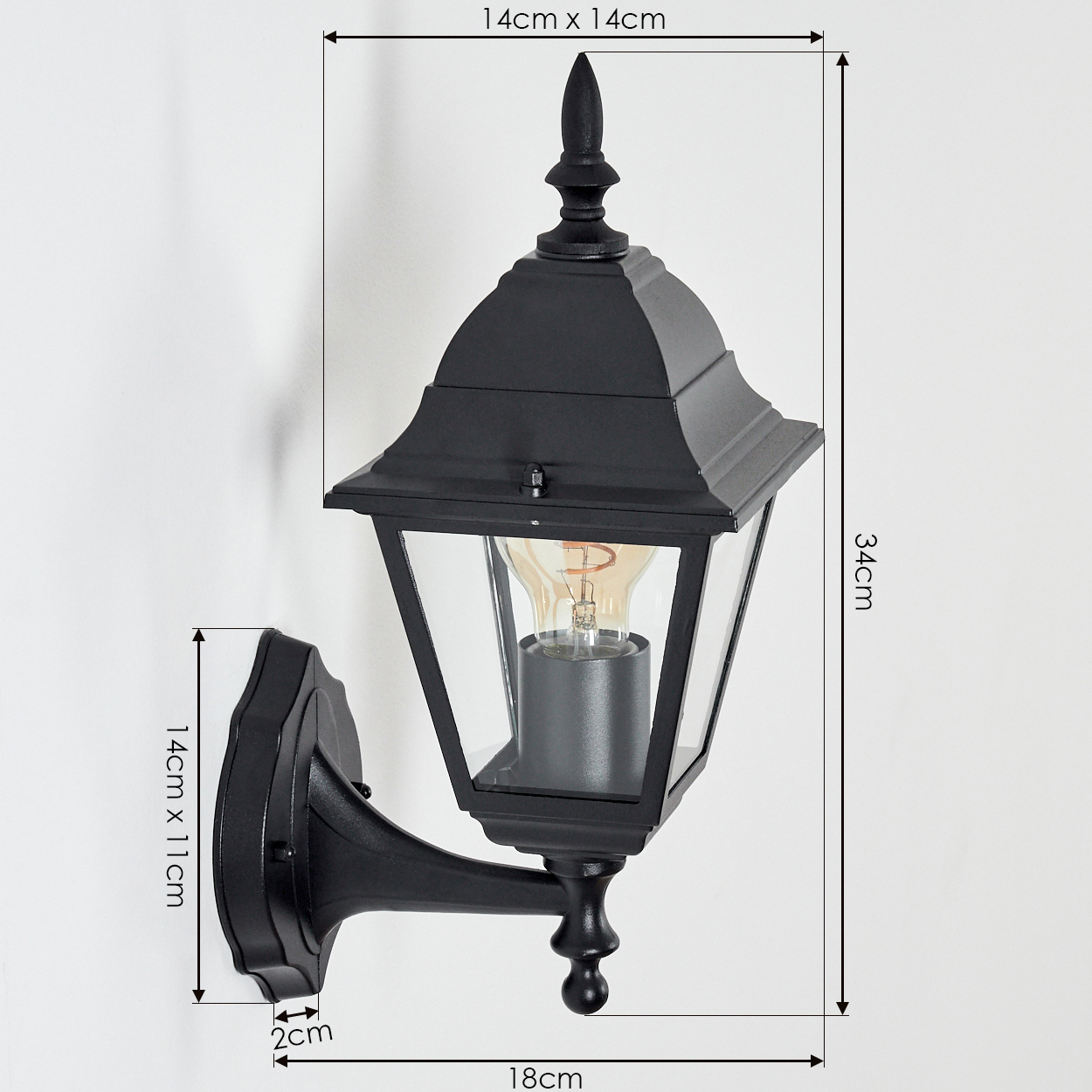Eine schwarze Außenwandleuchte mit klaren Glasscheiben, die eine brennende Glühbirne beherbergt. Sie ist an einer weißen Wand montiert, mit Größenangaben.