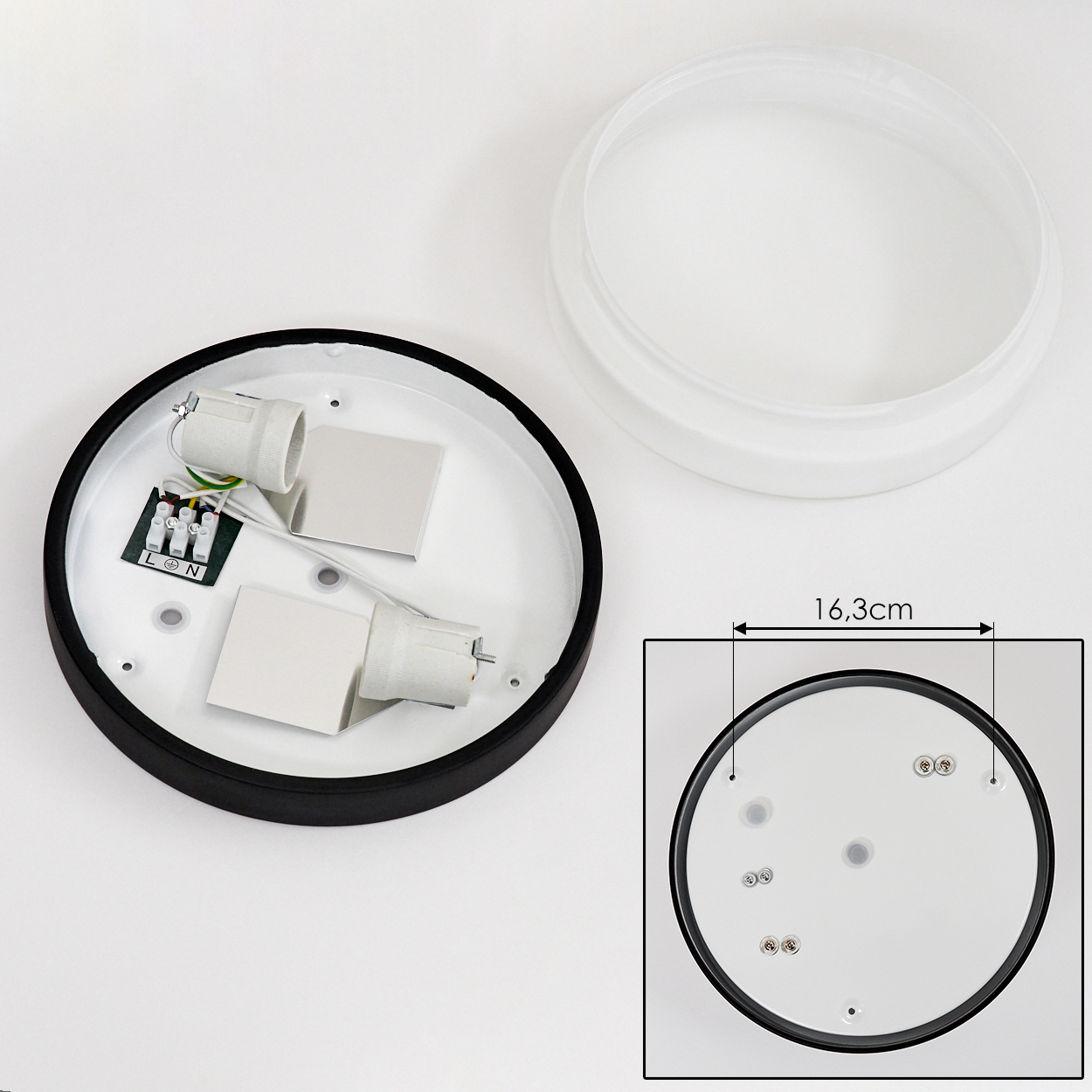 Eine zerlegte Deckenlampe mit weißem Sockel, schwarzem Rand und zwei Lampenfassungen. Eine separate Milchglasabdeckung und eine detaillierte Zeichnung sind abgebildet.