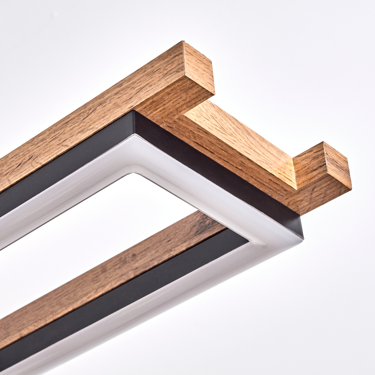 Nahaufnahme einer modernen Leuchte. Sie hat Holzbalken, schwarzes Metall und eine weiße Lichtquelle vor weißem Hintergrund.