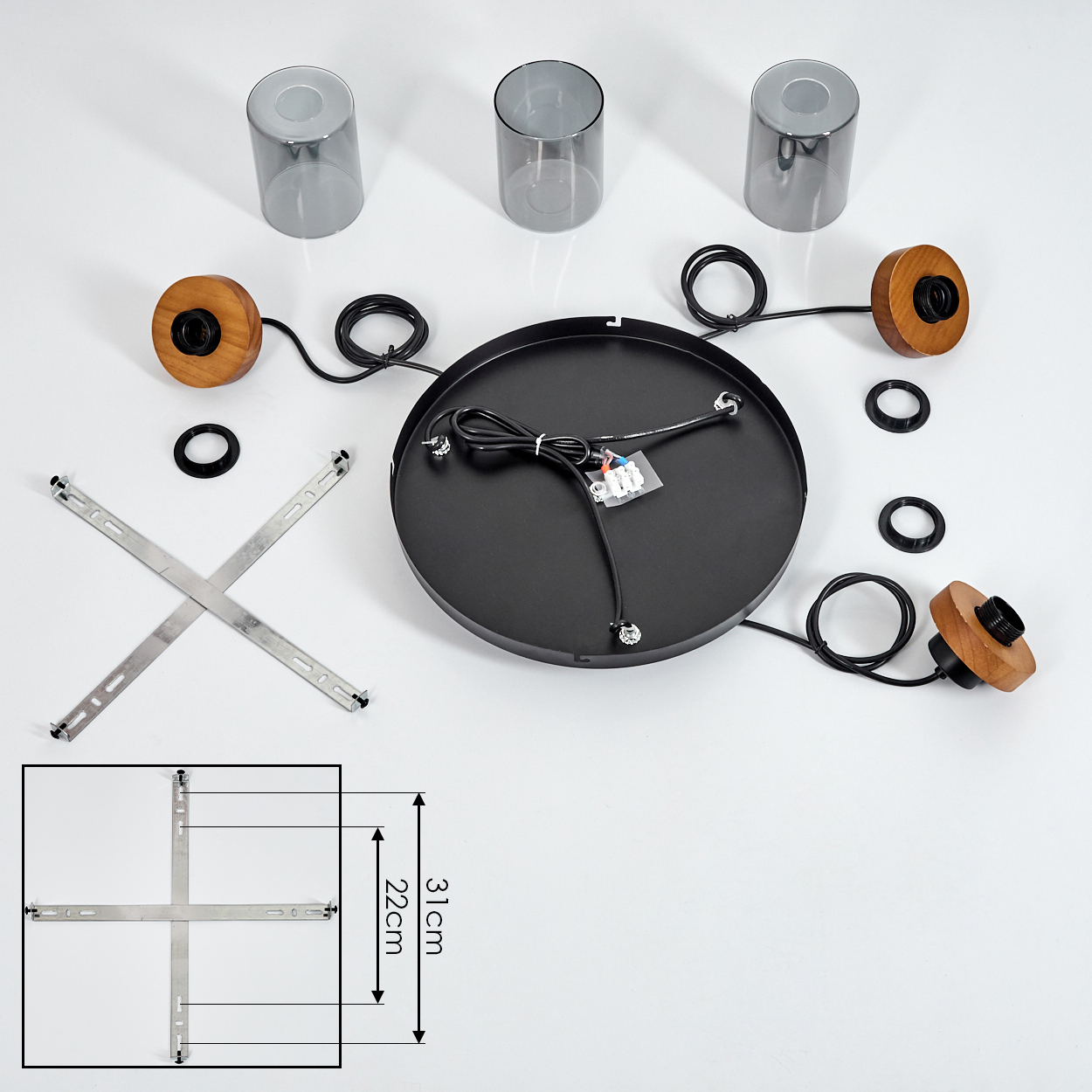 Draufsicht auf eine zerlegte Deckenleuchte. Zu den Komponenten gehören eine schwarze Platte, Holzvorrichtungen, Glasschirme, Metallstützen und Drähte.