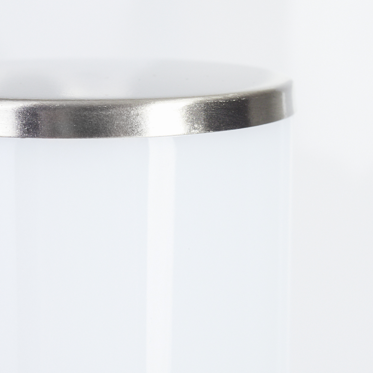 Nahaufnahme eines weißen, zylindrischen Objekts mit silbernem Metallrand. Das Objekt erscheint glatt vor weißem Hintergrund.