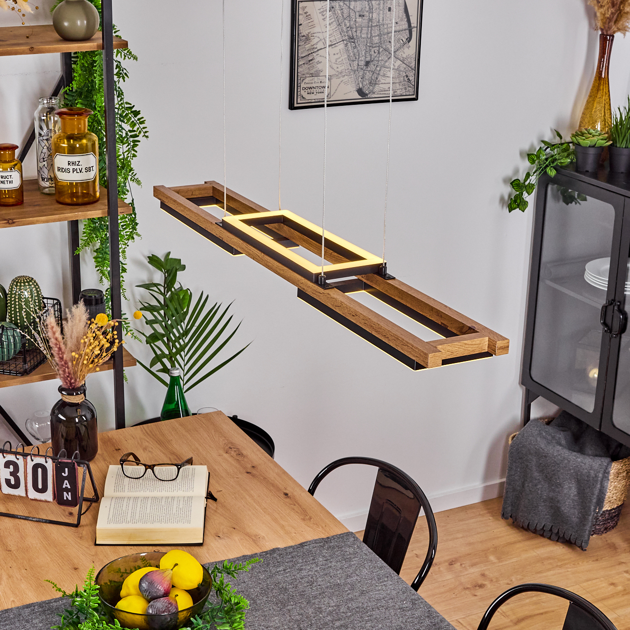 Ein Esszimmer mit Holztisch, Hängelampe, Regal mit Deko und Schrank mit Geschirr.