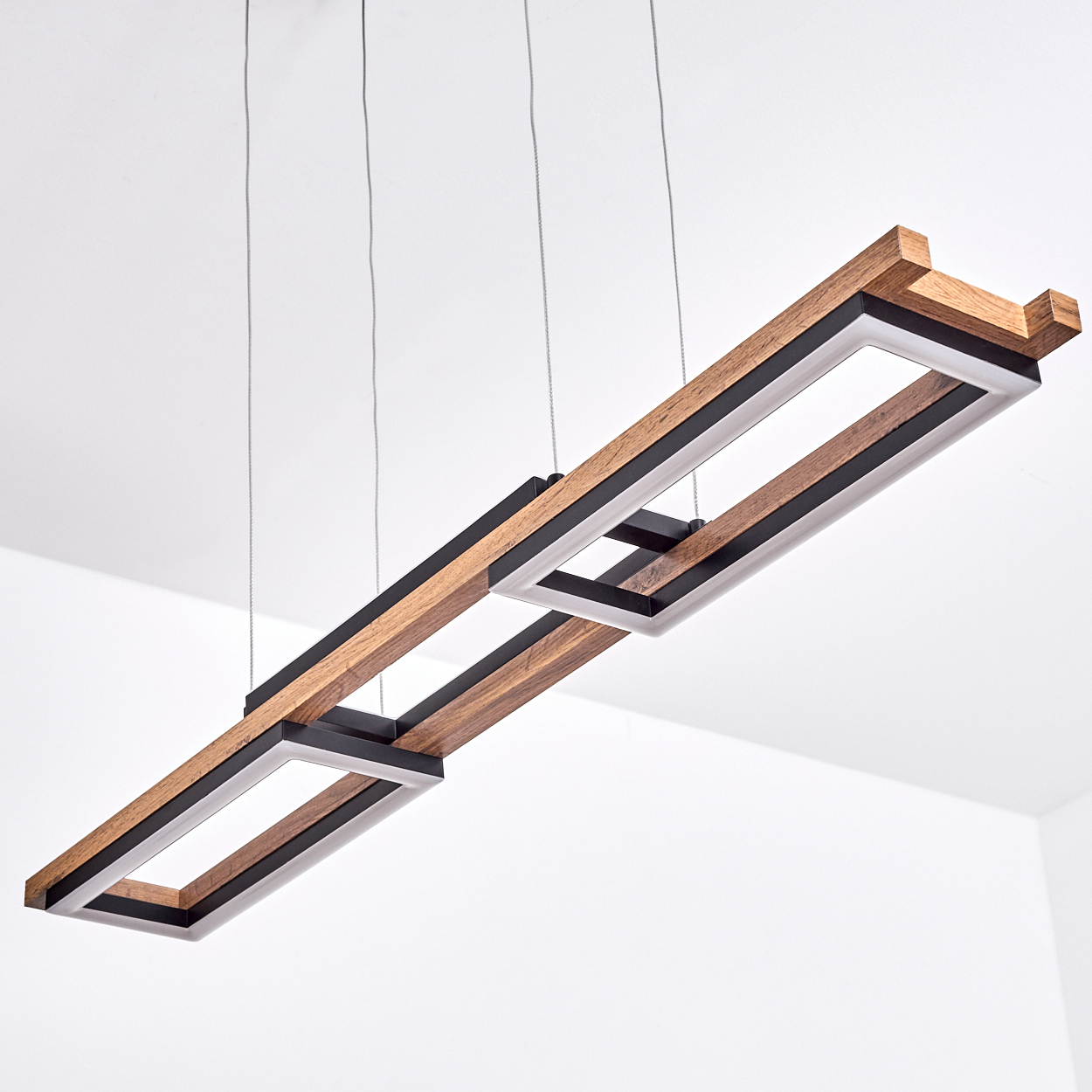 Eine moderne, rechteckige Holz-Pendelleuchte mit schwarzen und weißen Akzenten hängt von der Decke. Der Hintergrund ist weiß.