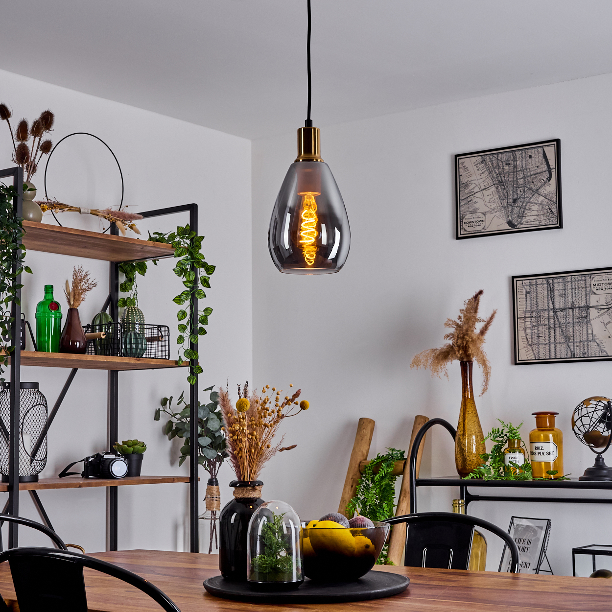Ein Esszimmer mit Hängelampe. Regale mit Pflanzen und Dekoration. Ein Tisch mit Dekoration. Karten an der weißen Wand.