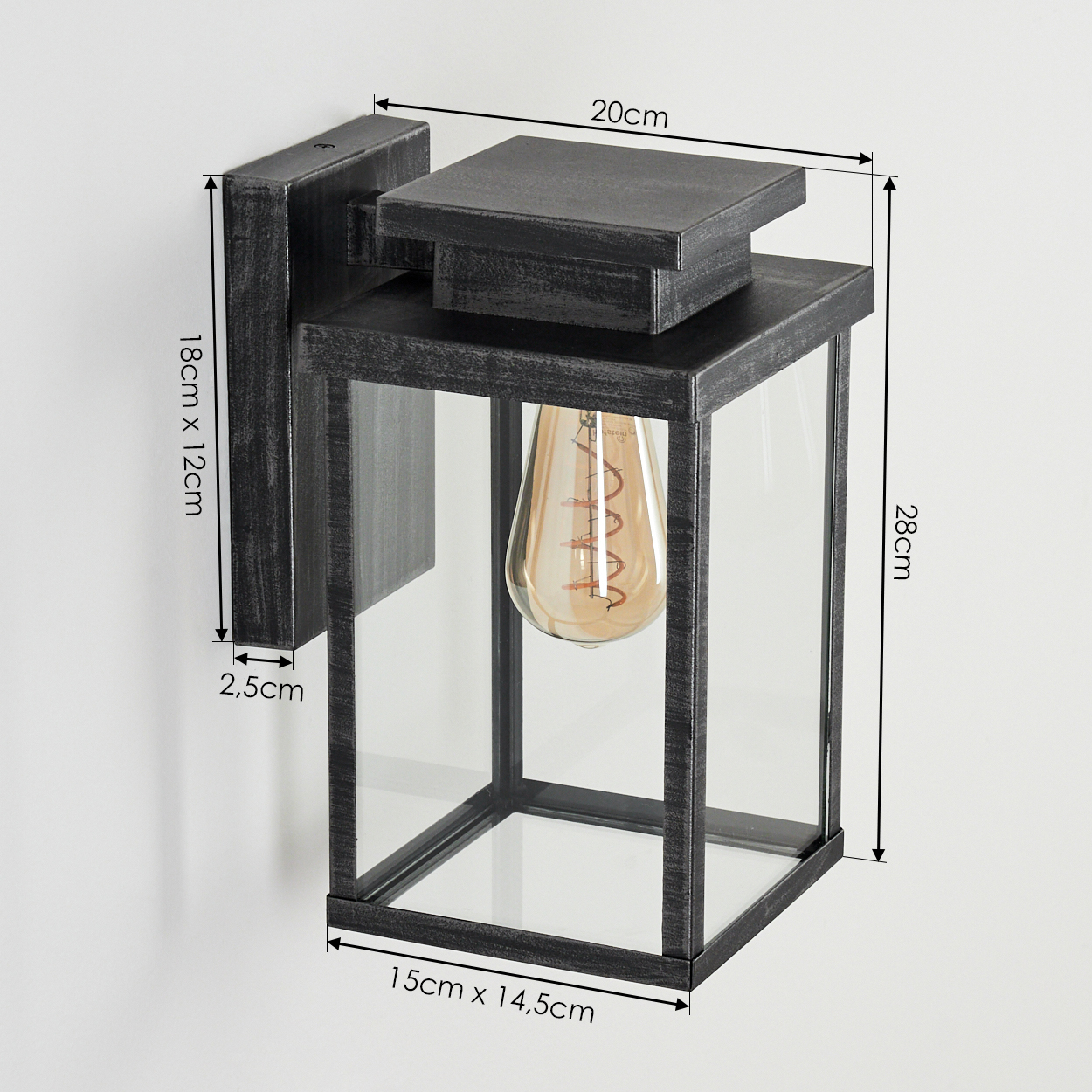 Eine Wandlaterne mit beschrifteten Maßen. Sie hat einen schwarzen Metallrahmen und klare Glasscheiben. Im Inneren hängt eine Edison-Glühbirne.