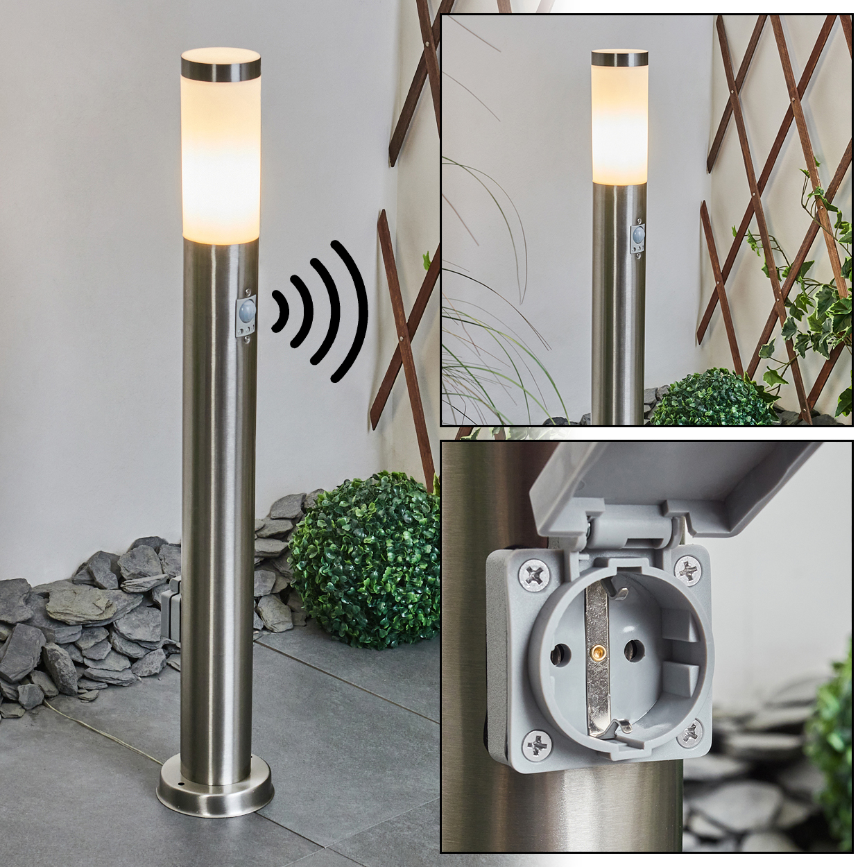 Eine Metall-Außenlampe mit Licht, Bewegungssensor und Steckdose. Der Hintergrund umfasst eine Wand, ein Spalier und Grün.