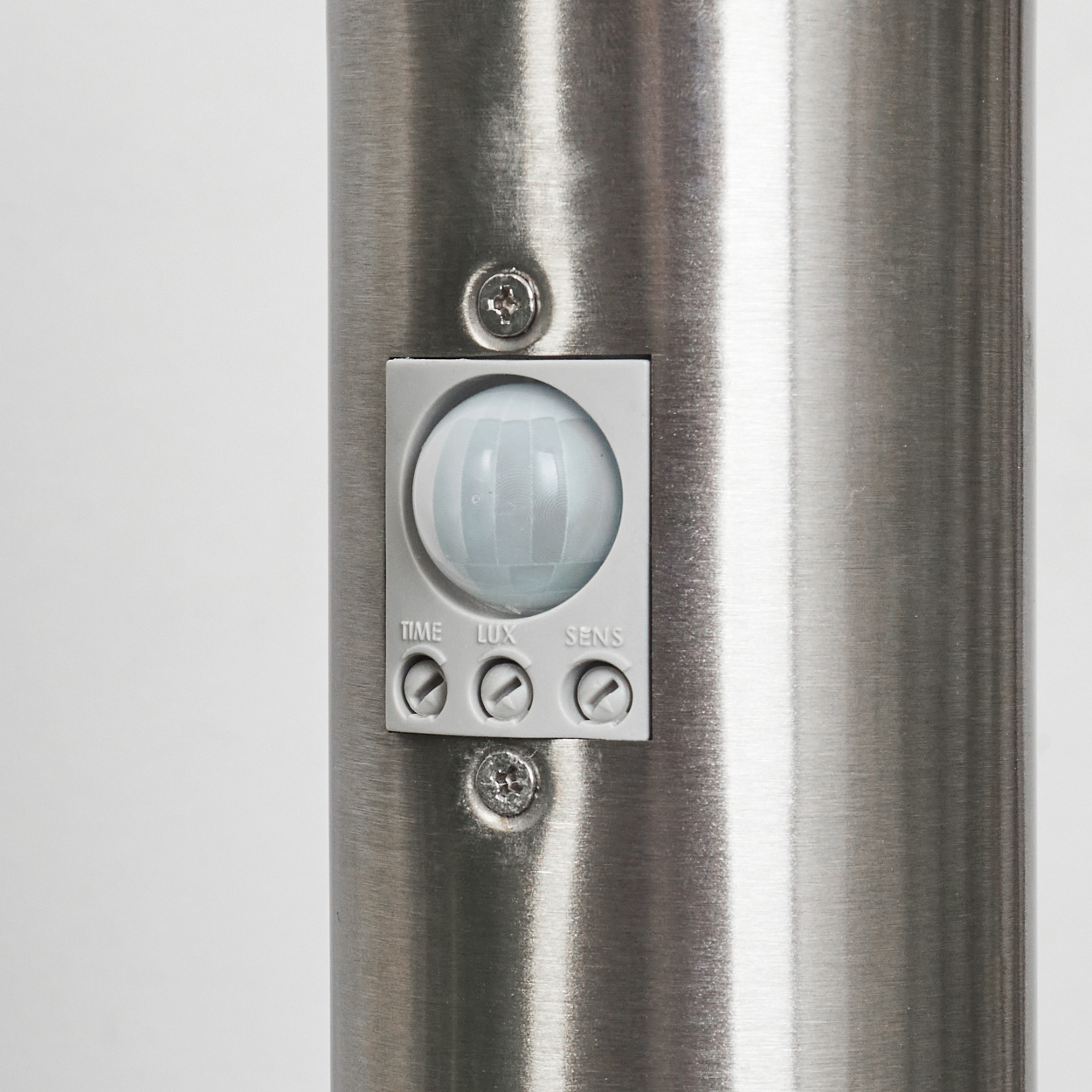 Nahaufnahme einer silbernen Metallstange mit einem Bewegungssensor. Der Sensor hat eine weiße Kuppel und drei Einstellräder.