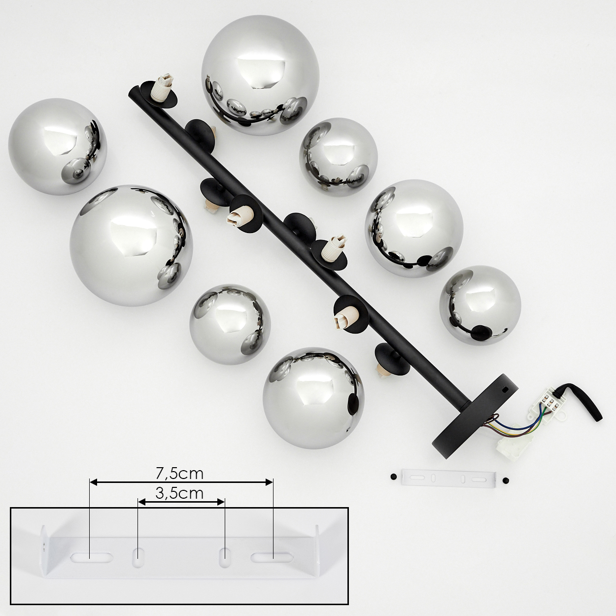 Eine moderne Deckenlampe mit silbernen Kugeln und einem schwarzen Arm. Eine weiße Halterung befindet sich im unteren Teil, mit Abmessungen.