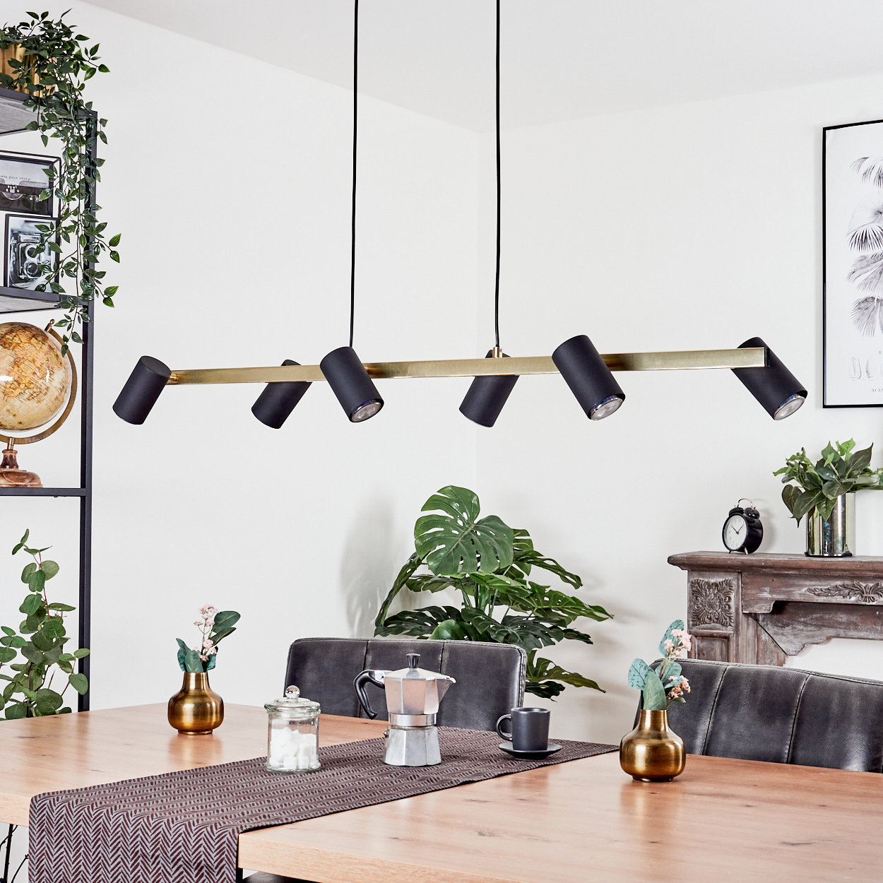 Ein modernes Esszimmer mit Holztisch, schwarzen Stühlen und stilvoller Leuchte. Pflanzen und Deko sorgen für Gemütlichkeit.