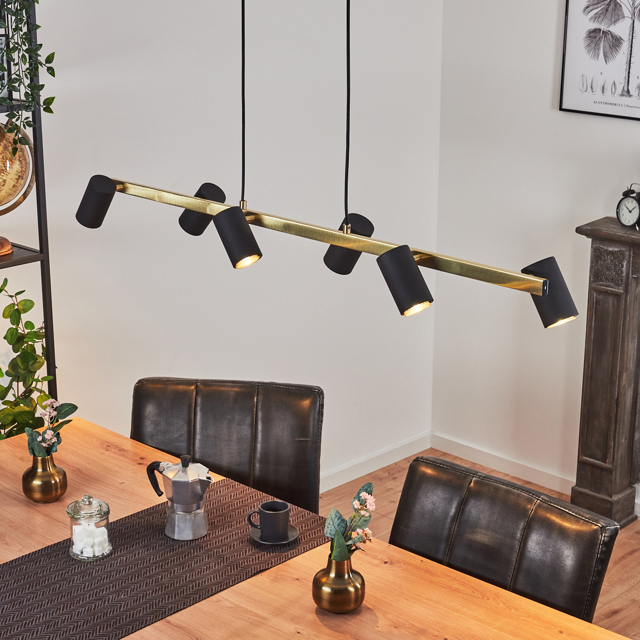 Ein modernes Esszimmer mit Holztisch, schwarzen Lederstühlen und einer stilvollen Lampe. Blumen und Kaffee stehen auf dem Tisch.