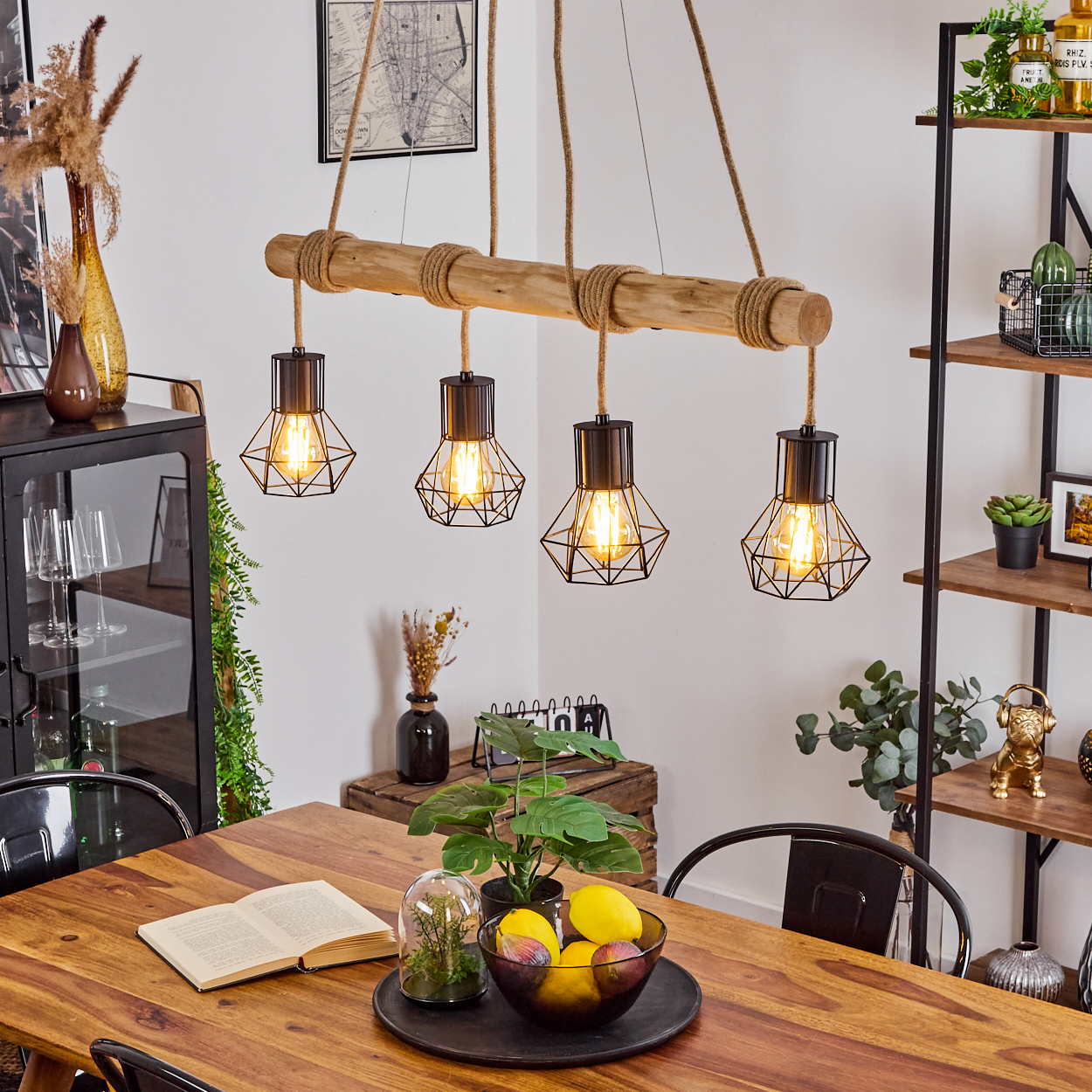 Ein Esszimmer mit Holztisch, Hängelampe und Bücherregal. Auf dem Tisch liegen ein Buch und eine Obstschale.