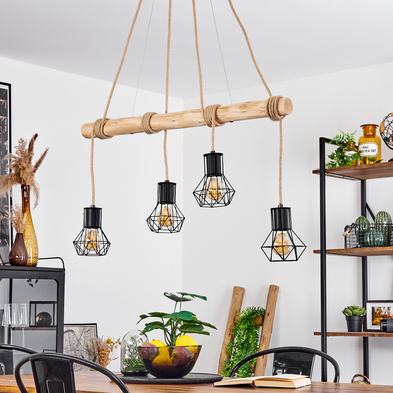 Ein Esszimmer mit einem Holzbalken-Kronleuchter mit vier Käfigglühbirnen, die über einem Tisch mit einer Obstschale hängen.